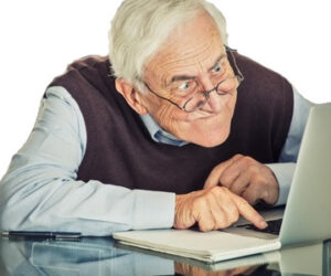 36816728-ltere-alter-mann-mit-computer-sitzt-am-tisch-auf-grauem-hintergrund-wand-Ältere-leute-und-technologie